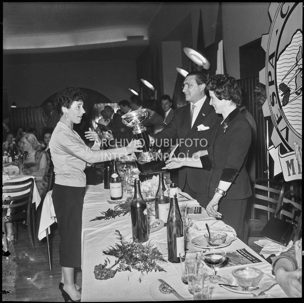 Il presidente del Vespa Club Milano Renato Tassinari ed una donna consegnano un premio ad una delle vincitrici della terza edizione dell'Audax internazionale vespistico femminile durante il banchetto organizzato del Vespa Club Milano<br>215344