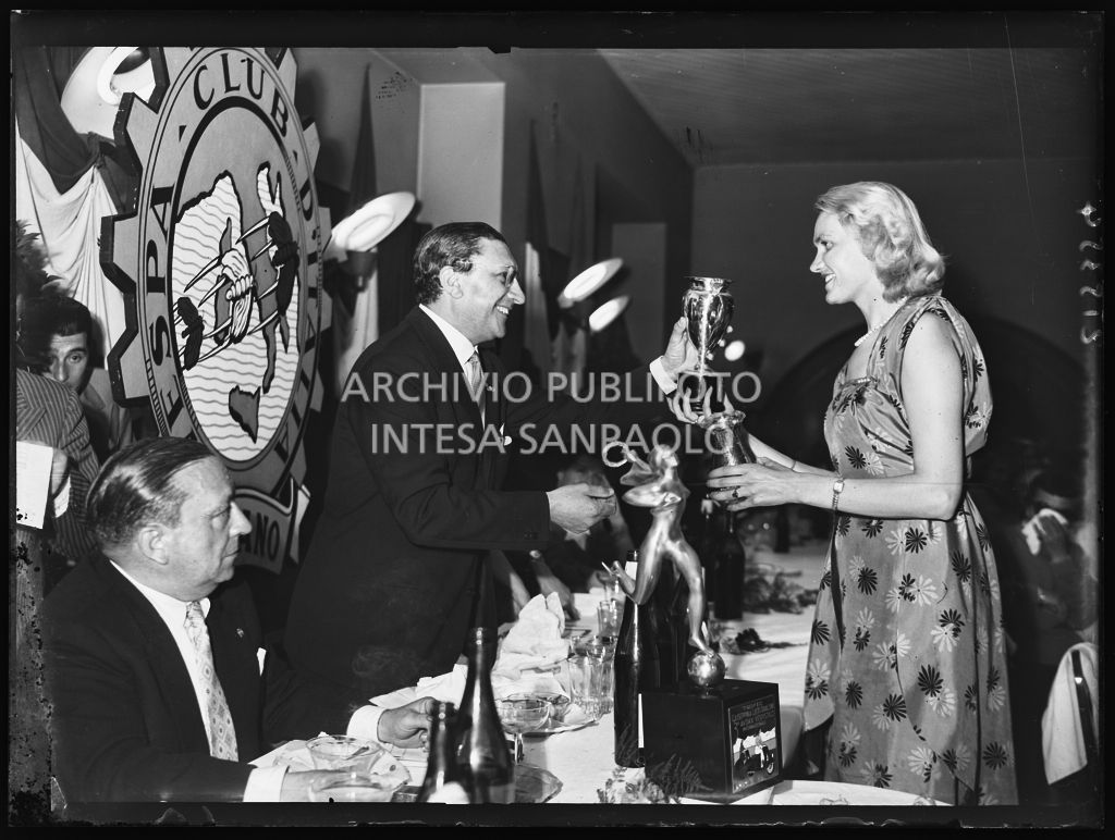 Il presidente del Vespa Club Milano Renato Tassinari consegna un premio ad una delle vincitrici della terza edizione dell'Audax internazionale vespistico femminile durante il banchetto organizzato del Vespa Club Milano<br>215354