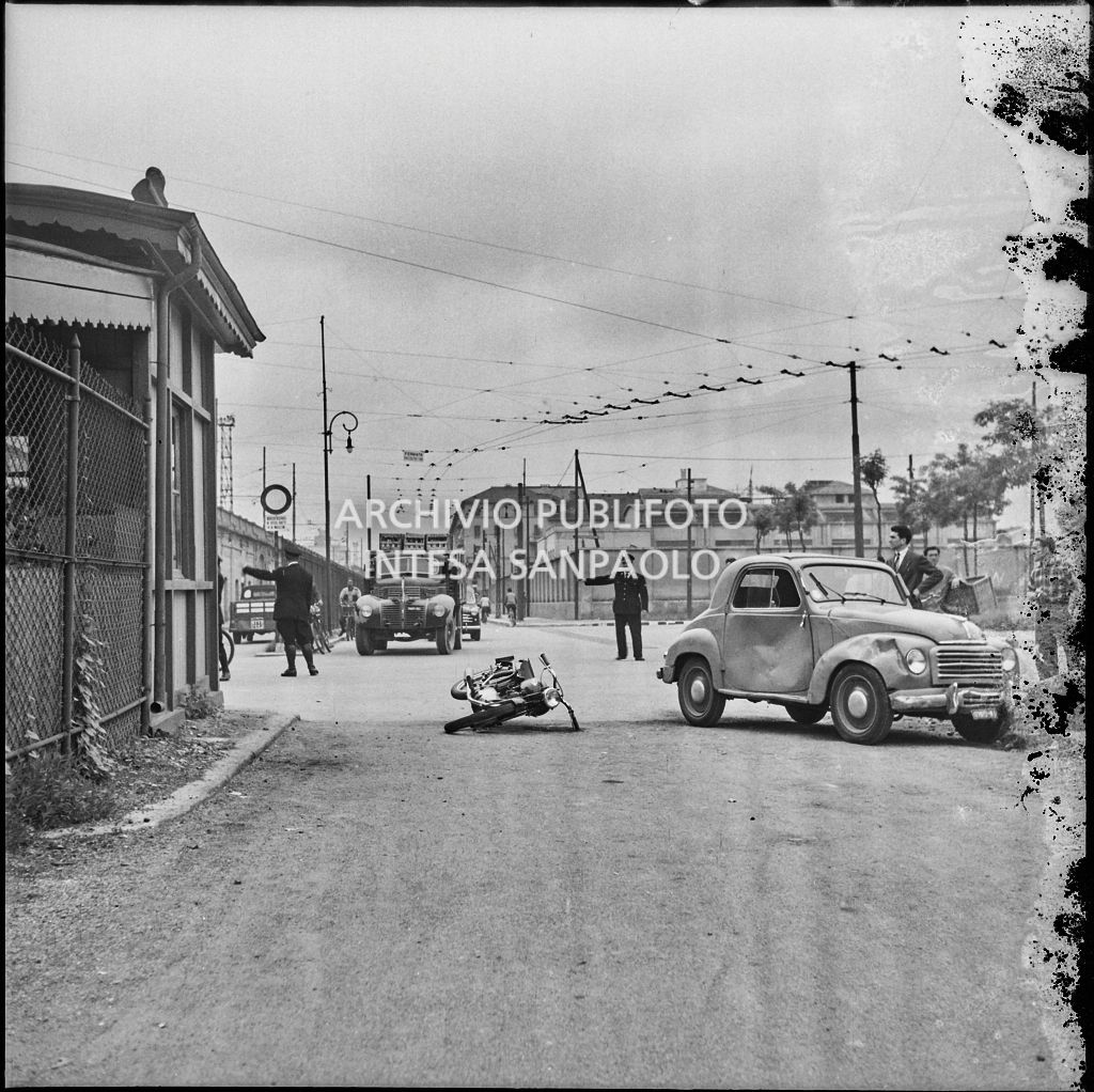 Gli agenti di polizia dirigono il traffico in seguito u un incidente tra un'automobile Fiat 500 Topolino e una motocicletta avvenuto ad un incrocio di Milano nei pressi di un sottopassaggio<br>216027