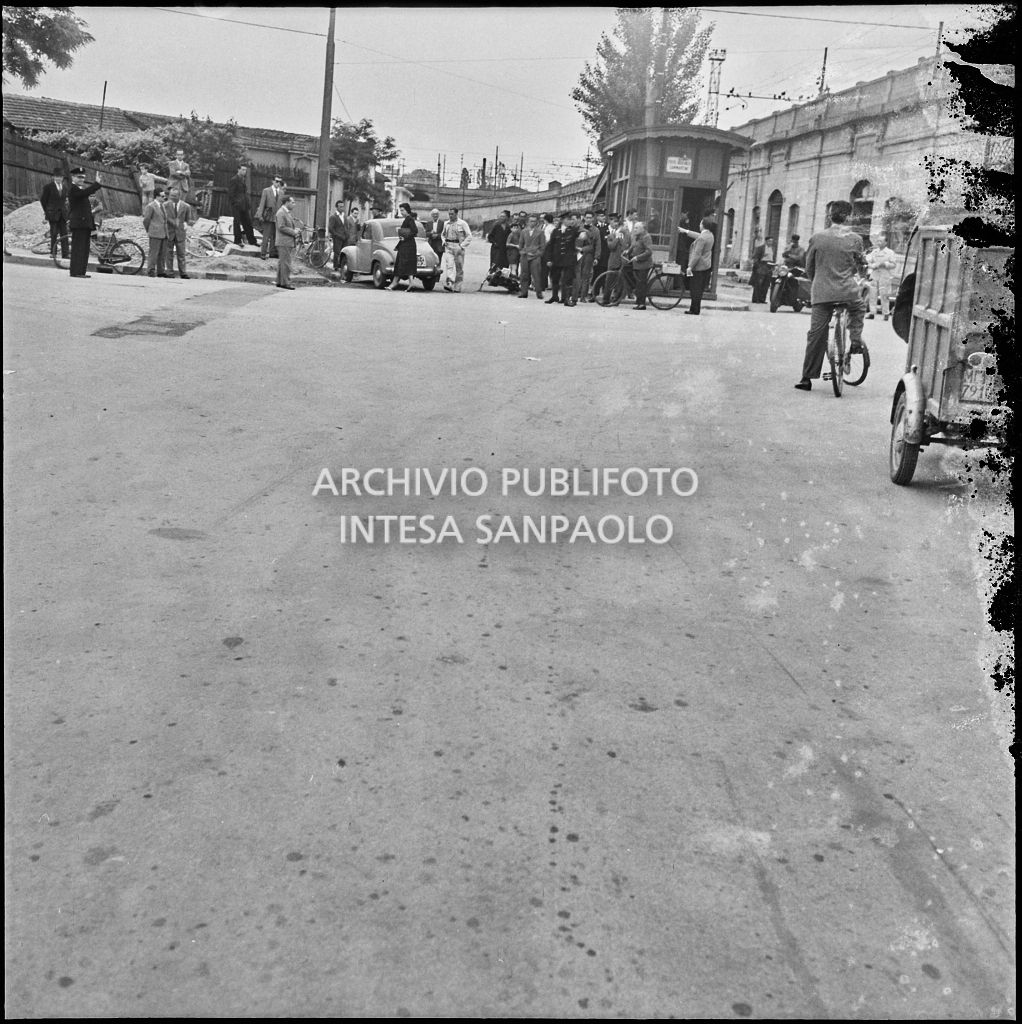 Incidente tra una motocicletta e un'automobile Fiat 500 Topolino avvenuto a un incrocio a Milano nei pressi di un sottopassaggio ferroviario con folla di curiosi<br>216038