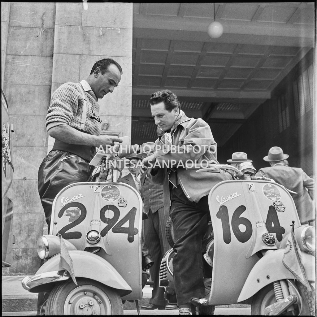 Il concorrente Alberto Castellino del Vespa Club di Pallanza (numero di gara 294) in un momento di pausa dalla competizione sportiva 1000 Km Vespistica del 1954 in piazza della Vittoria a Brescia<br>216184