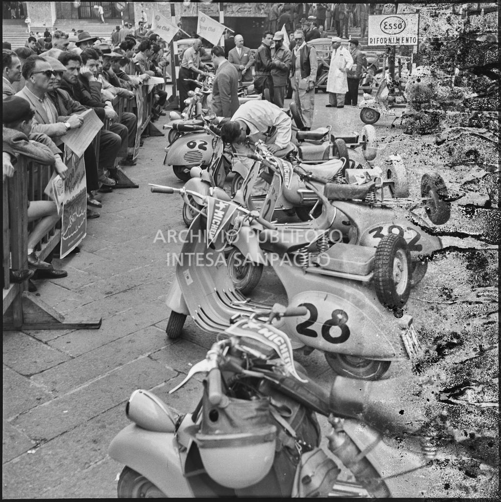 Scooter Vespa parcheggiate in piazza della Vittoria a Brescia in occasione della competizione sportiva 1000 Km Vespistica del 1954<br>216217