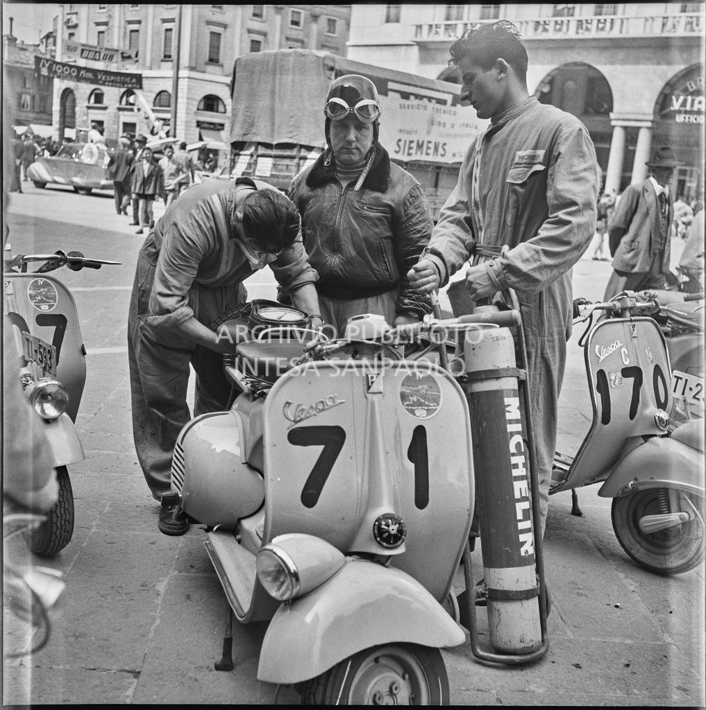 Controllo pressione gomme di una Vespa della competizione sportiva 1000 Km Vespistica del 1954 in piazza della Vittoria a Brescia<br>216224