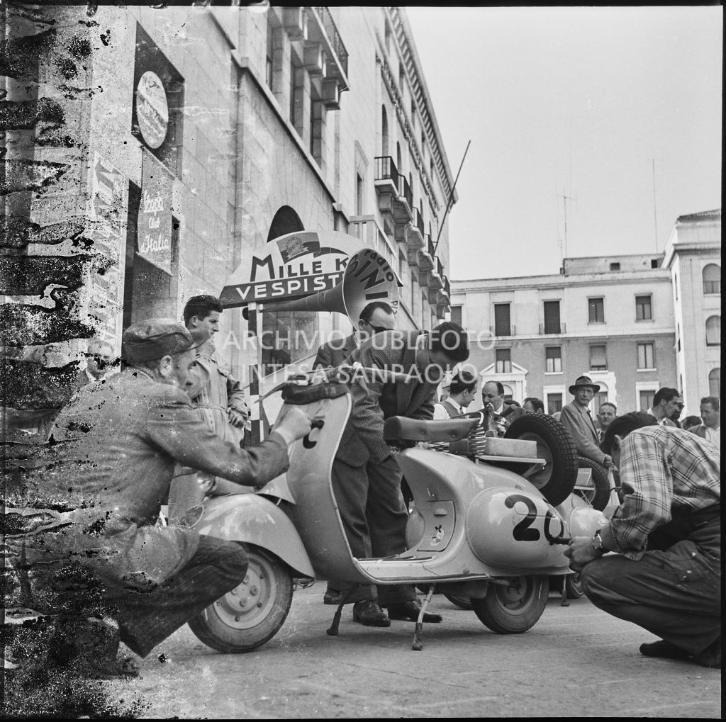 Scrittura del numero di gara su uno scooter Vespa della competizione sportiva 1000 Km Vespistica del 1954 in piazza della Vittoria a Brescia<br>216261