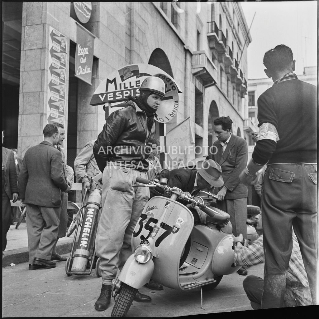 Il concorrente Sergio Proserpio del Vespa Club di Chiasso (numero di gara 357) in piazza della Vittoria a Brescia in occasione della competizione sportiva 1000 Km Vespistica del 1954<br>216273