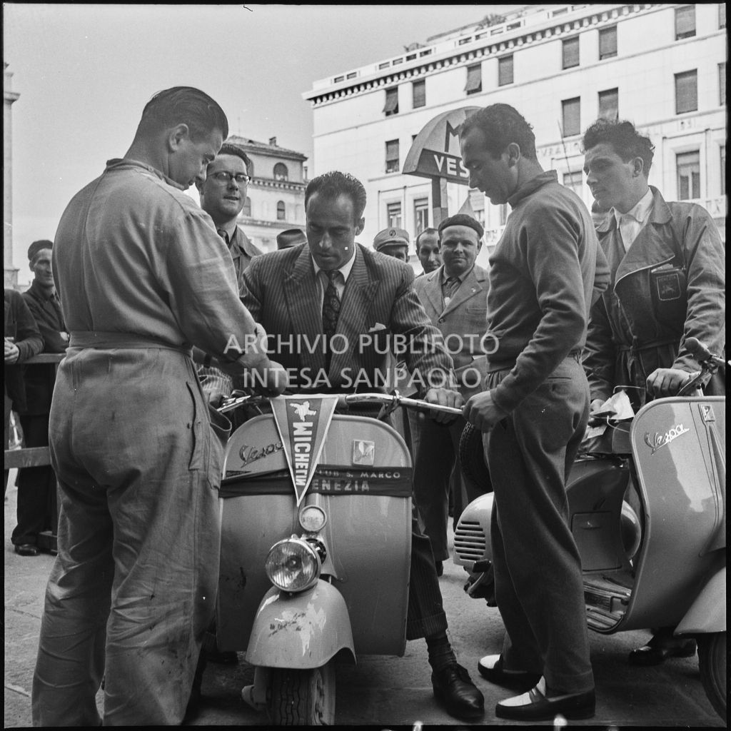 Alcuni uomini in piazza della Vittoria a Brescia in occasione della competizione sportiva 1000 Km Vespistica del 1954<br>216276