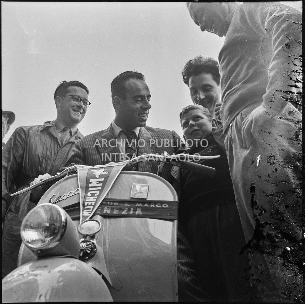 Alcune persone intorno ad una Vespa in occasione della  competizione sportiva 1000 Km Vespistica del 1954 a Brescia<br>216311