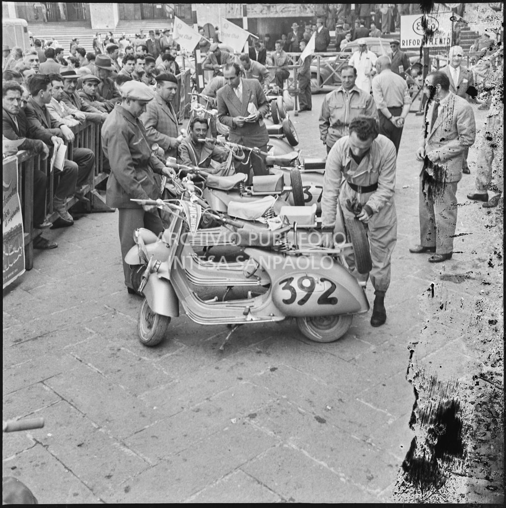 Controllo degli scooter Vespa in piazza della Vittoria a Brescia in occasione della competizione sportiva 1000 Km Vespistica del 1954<br>216313