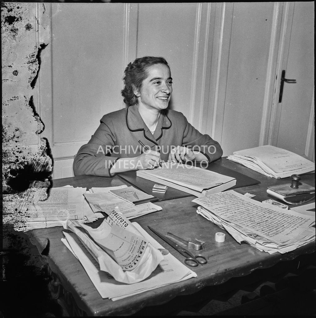 Una donna seduta alla scrivania in occasione del convegno di studio sulle condizioni del lavoratore nell'impresa industriale organizzata nei Chiostri di San Barnaba a Milano dalla Società Umanitaria. Sulla scrivania una busta da lettere della Publifoto<br>216346