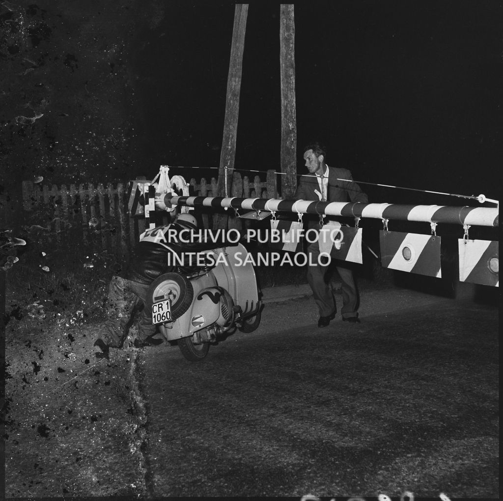 Un concorrente della competizione sportiva 1000 Km Vespistica del 1954 supera un passaggio a livello ferroviario<br>216353