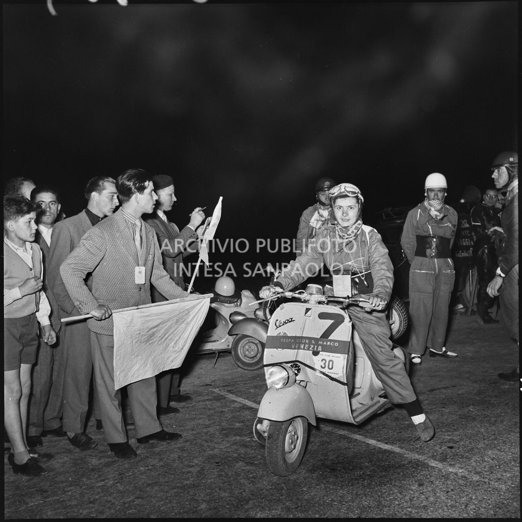 La concorrente del Vespa Club di Venezia (numero di gara 7) in un momento di pausa dalla competizione sportiva 1000 Km Vespistica del 1954<br>216359