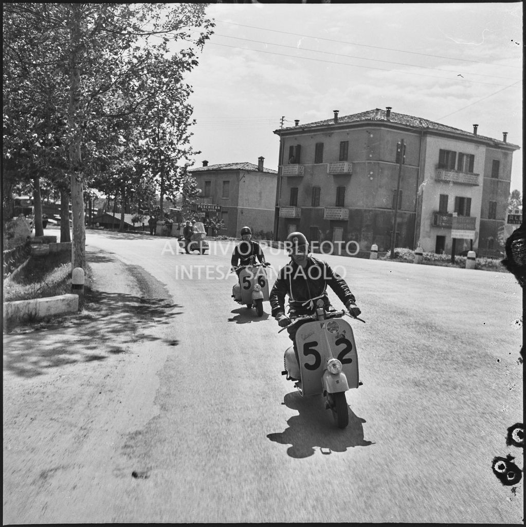 I concorrenti Benito Pagani del Vespa Club di Chiari (numero di gara 52) e Mario Pagani del Vespa Club di Chiari (numero di gara 56) a Peschiera del Garda durante la competizione sportiva 1000 Km Vespistica del 1954<br>216388