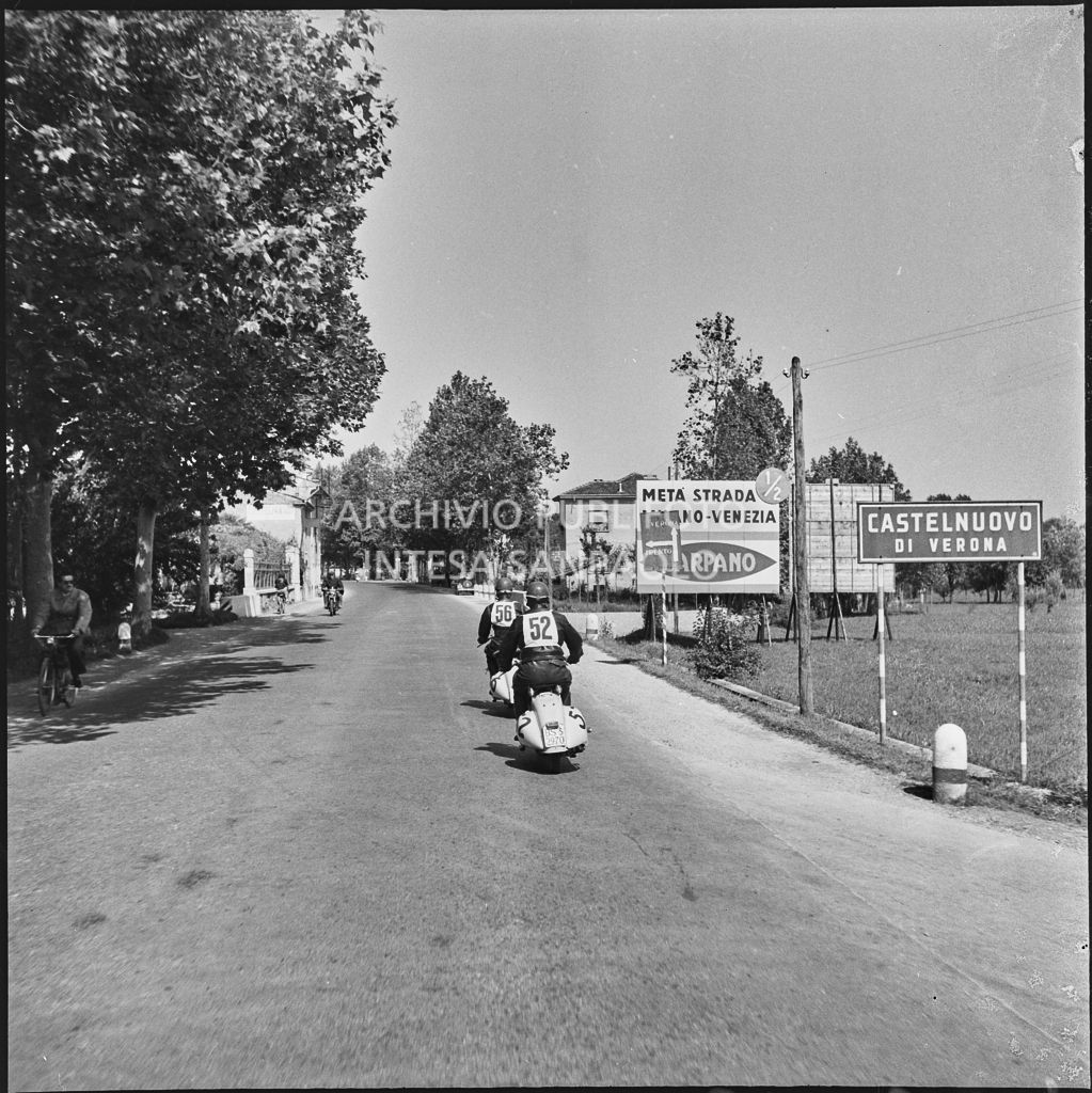 I concorrenti Benito Pagani del Vespa Club di Chiari (numero di gara 52) e Mario Pagani del Vespa Club di Chiari (numero di gara 56) a Castelnuovo di Verona durante la competizione sportiva 1000 Km Vespistica del 1954<br>216389