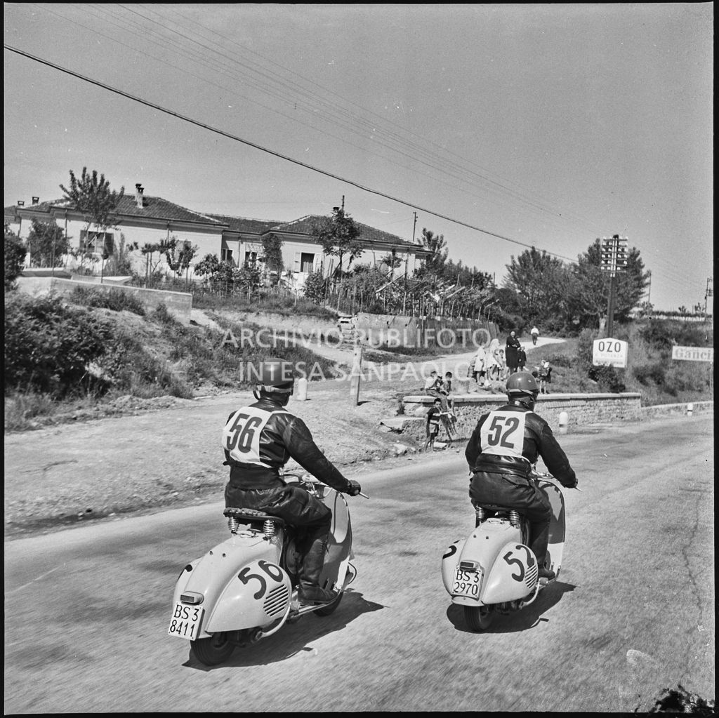 I concorrenti Benito Pagani del Vespa Club di Chiari (numero di gara 52) e Mario Pagani del Vespa Club di Chiari (numero di gara 56) durante la competizione sportiva 1000 Km Vespistica del 1954<br>216390
