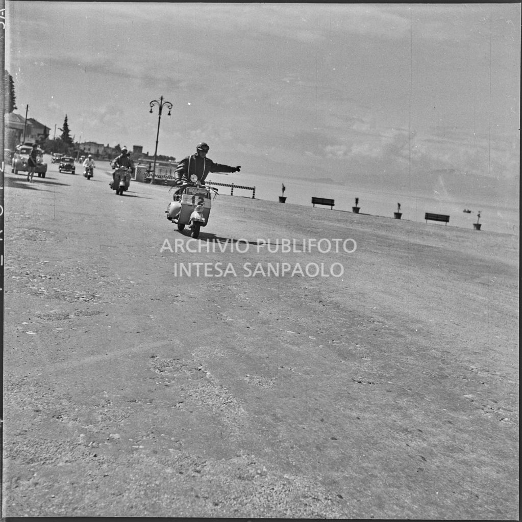 Due concorrenti (numero di gara 11 e 12) a Peschiera del Garda durante la competizione sportiva 1000 Km Vespistica del 1954<br>216414