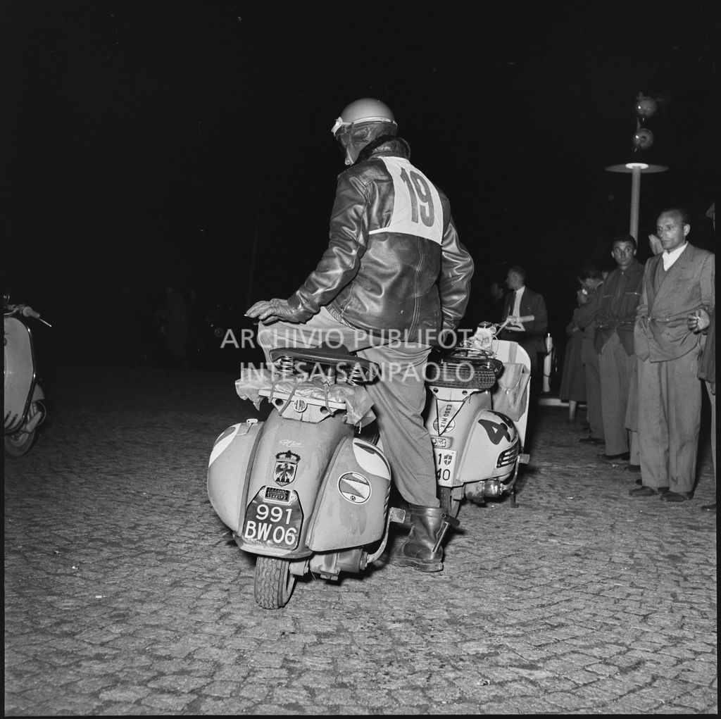 Il concorrente Vaucher del Vespa Club di Parigi (numero di gara 19) durante una pausa dalla competizione sportiva 1000 Km Vespistica del 1954<br>216437