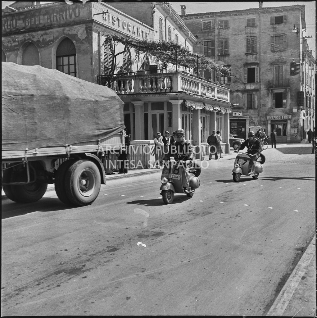 Il concorrente Bruno Camplani del Vespa club di Lecco (numero di gara 18) ed un'altro concorrente (numero di gara 17) durante la competizione sportiva 1000 Km Vespistica del 1954<br>216443