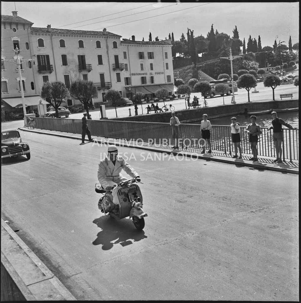 Un concorrente (numero di gara 13) durante la competizione sportiva 1000 Km Vespistica del 1954 a Peschiera del Garda<br>216477