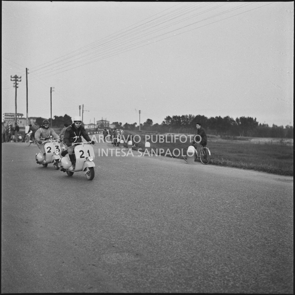 I concorrenti del Vespa Club di Brescia Giorgio Filippini (numero di gara 21) e Giovanni Mariani (numero di gara 23) durante la competizione sportiva 1000 Km Vespistica del 1954<br>216485