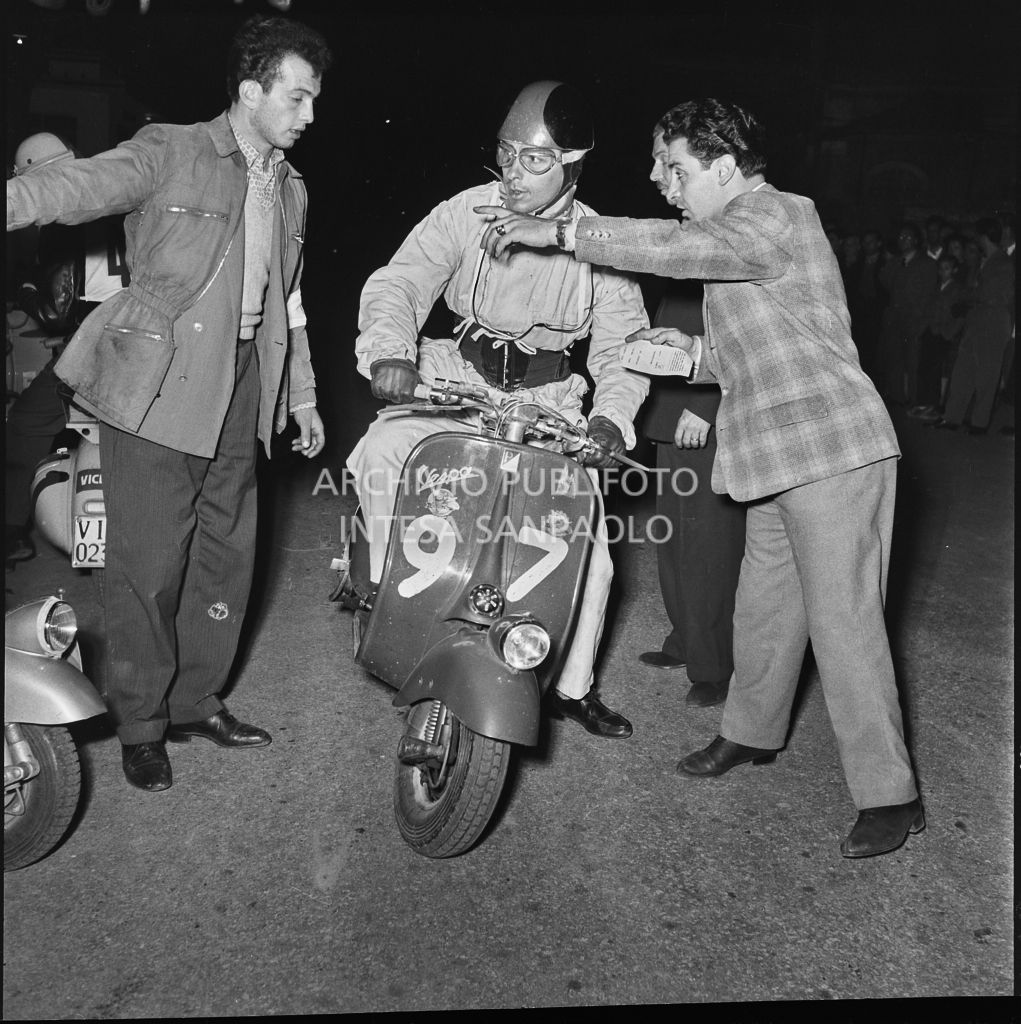 Alcuni uomini danno indicazioni ad un concorrente (numero di gara 97) della competizione sportiva 1000 Km Vespistica del 1954<br>216486