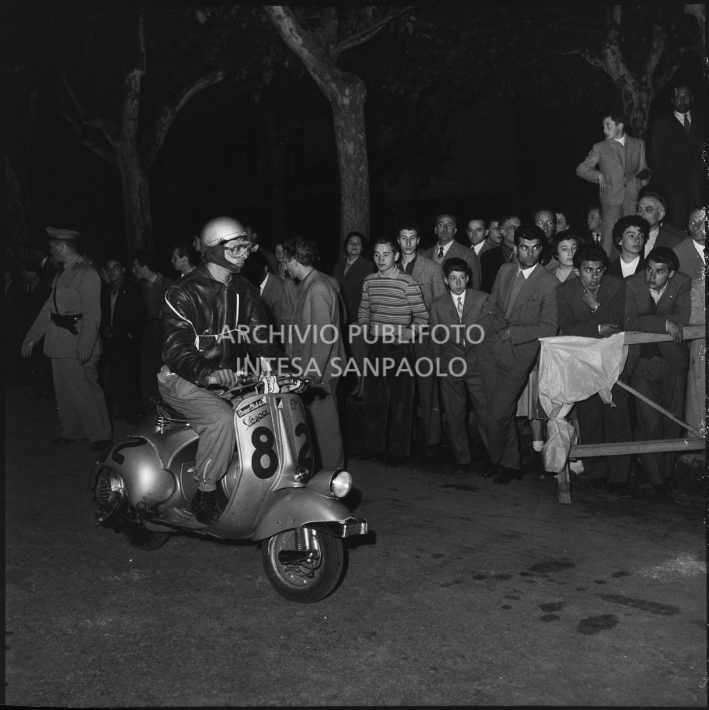 Arrivo di un concorrente (numero di gara 82) al controllo tempi della competizione sportiva 1000 Km Vespistica del 1954<br>216492