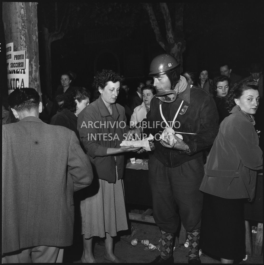 Un concorrente del Vespa Club di Venezia riceve del cibo durante una pausa dalla competizione sportiva 1000 Km Vespistica del 1954<br>216496