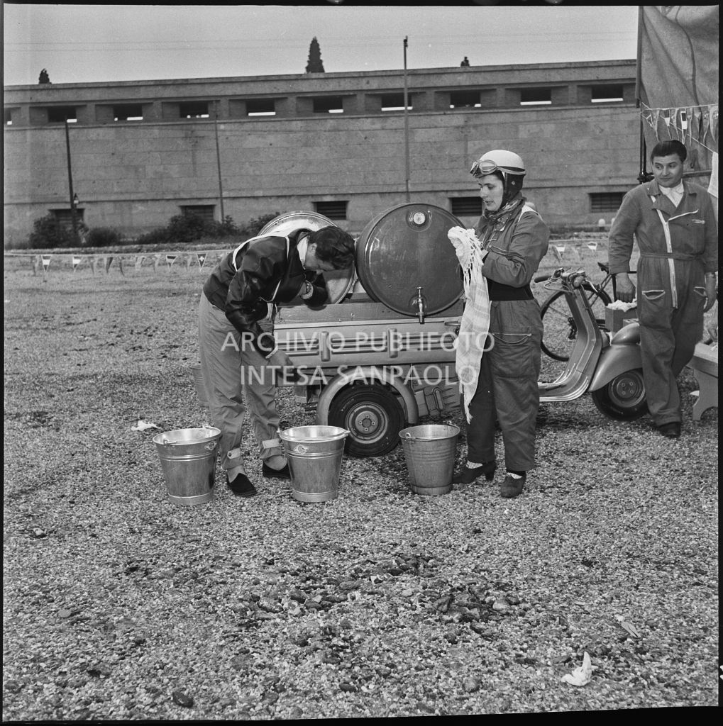Due concorrenti si rinfrescano durante una pausa dalla competizione sportiva 1000 Km Vespistica del 1954<br>216505