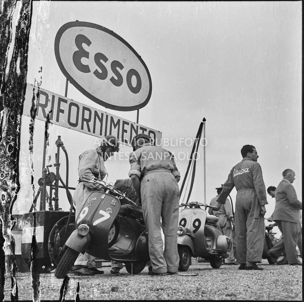Controllo della Vespa di un concorrente (numero di gara 97) da parte di alcuni meccanici durante una pausa dalla competizione sportiva 1000 Km Vespistica del 1954<br>216521