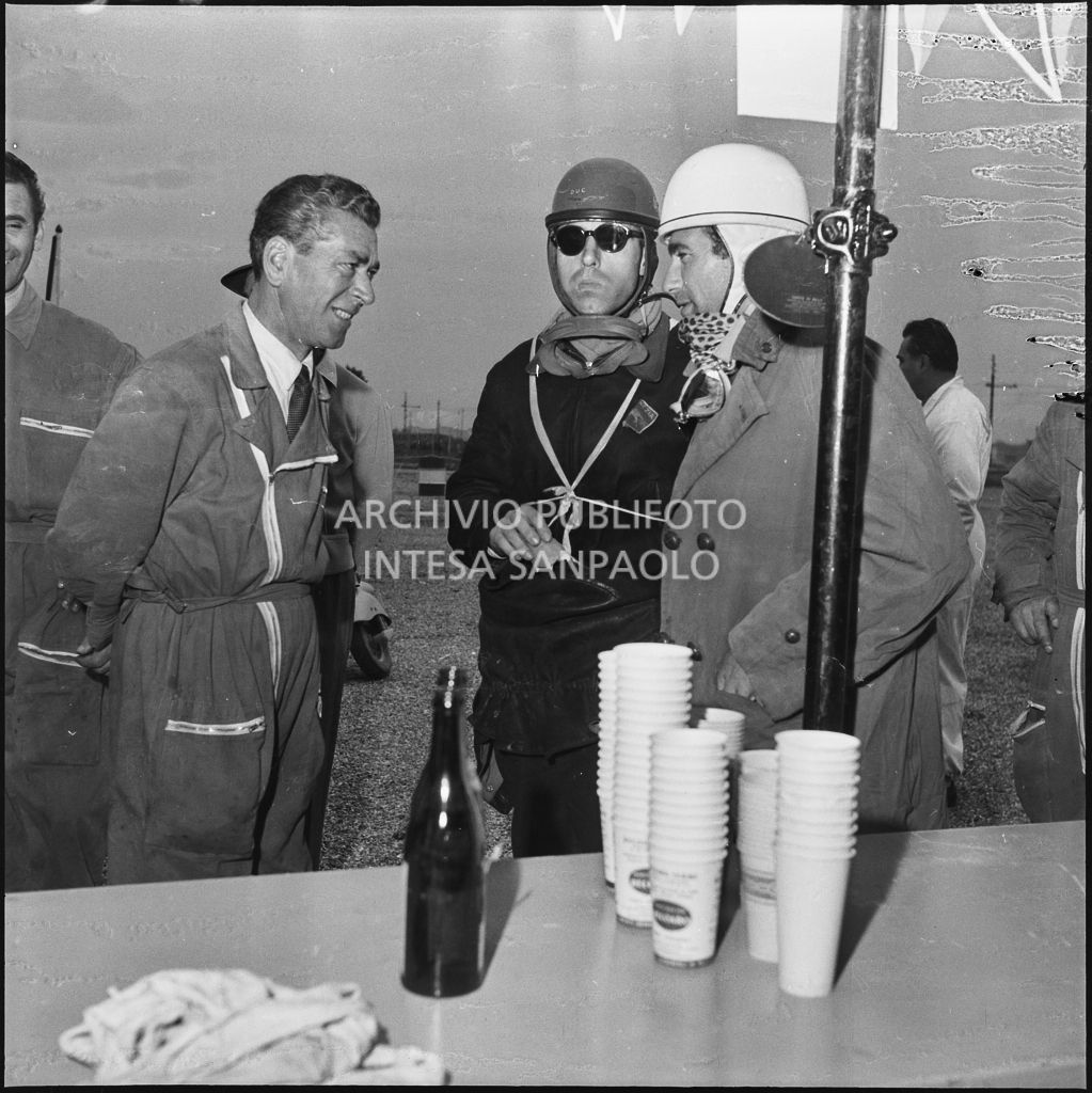 Due concorrenti conversano con un meccanico durante una pausa dalla competizione sportiva 1000 Km Vespistica del 1954<br>216542