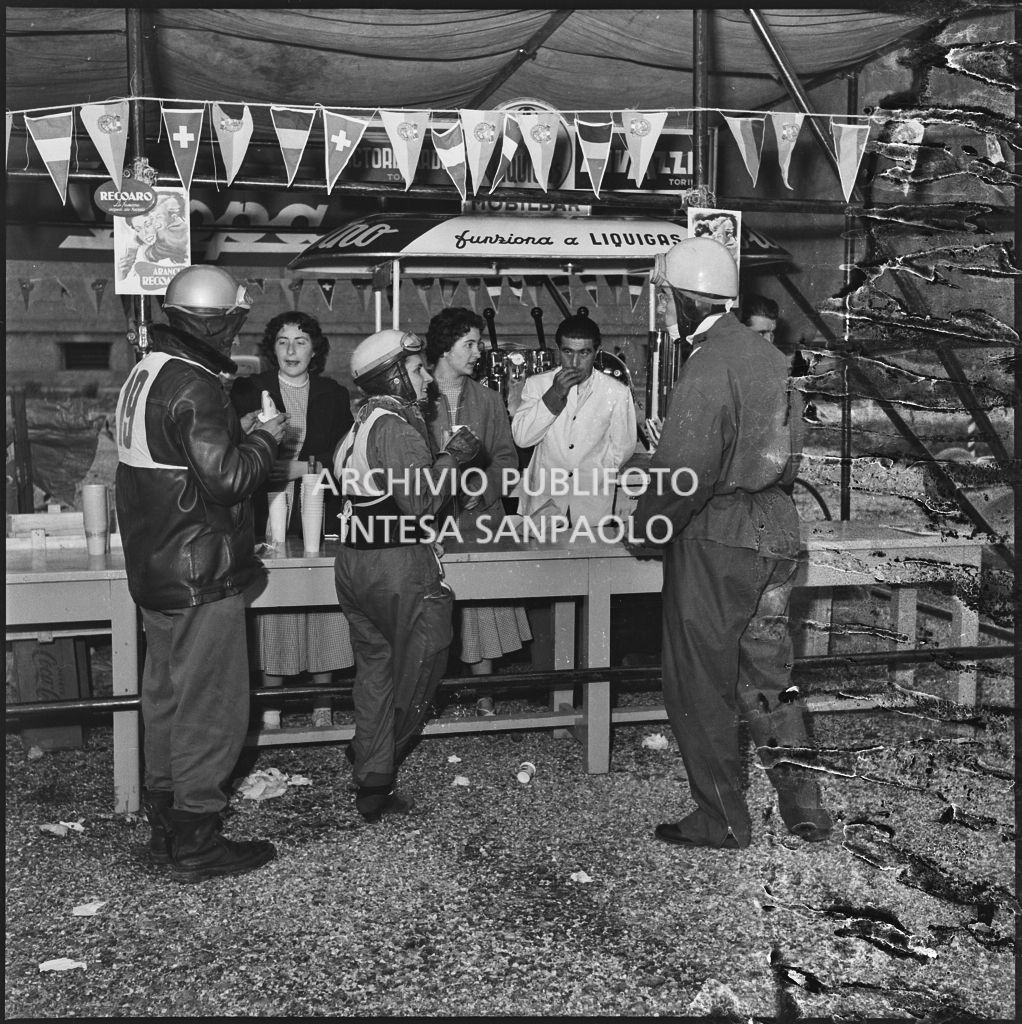 Alcuni concorrenti al punto ristoro durante una pausa dalla competizione sportiva 1000 Km Vespistica del 1954<br>216556