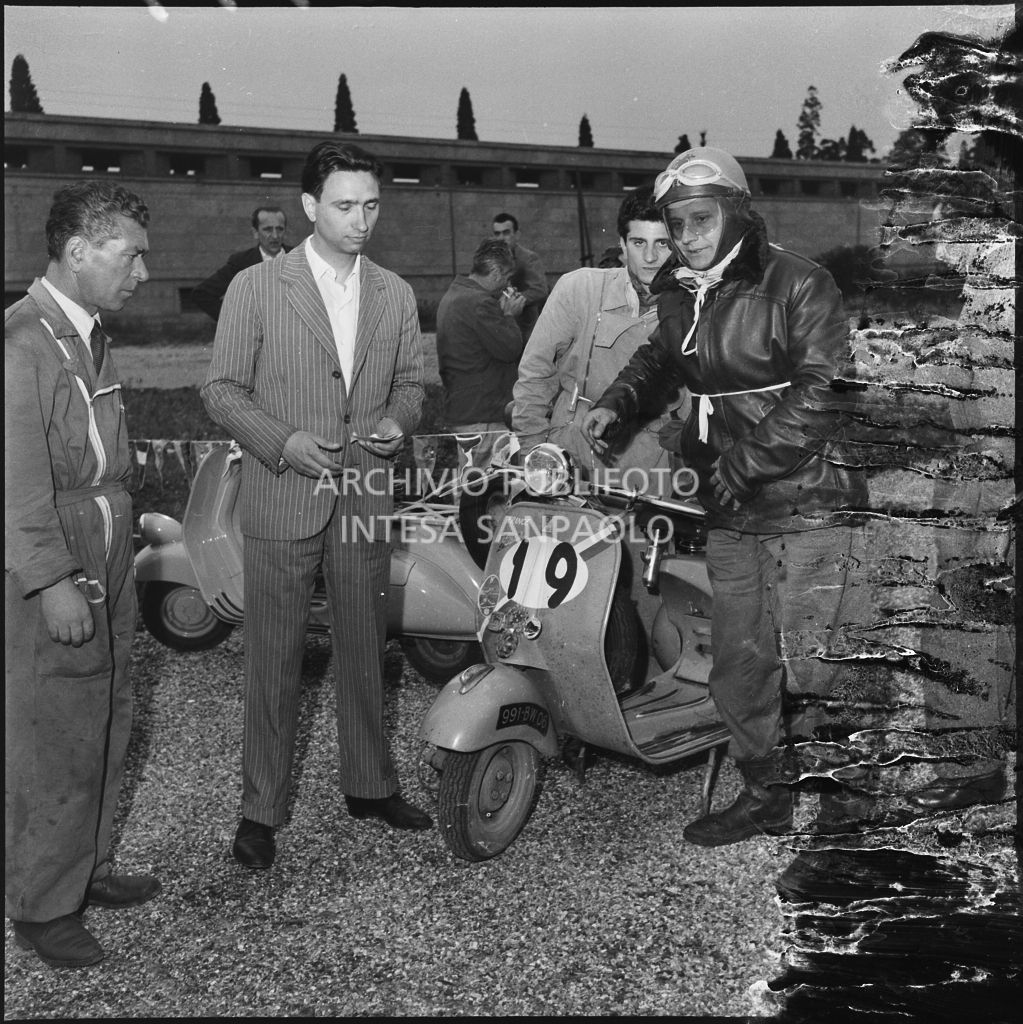 Il concorrente Vaucher del Vespa Club di Parigi (numero di gara 19) durante una pausa dalla competizione sportiva 1000 Km Vespistica del 1954<br>216557 bis