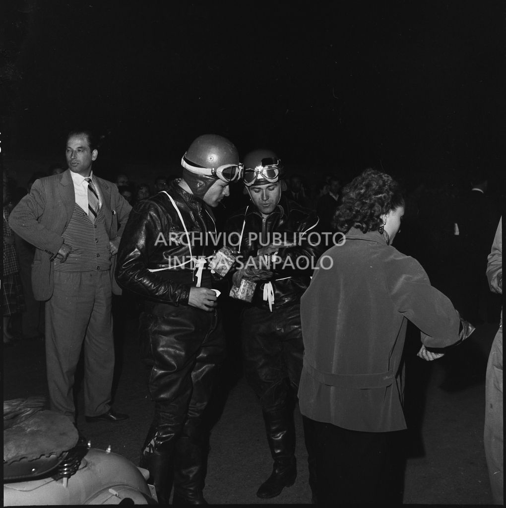 Due concorrenti controllano l'ora durante una pausa dalla competizione sportiva 1000 Km Vespistica del 1954<br>216602