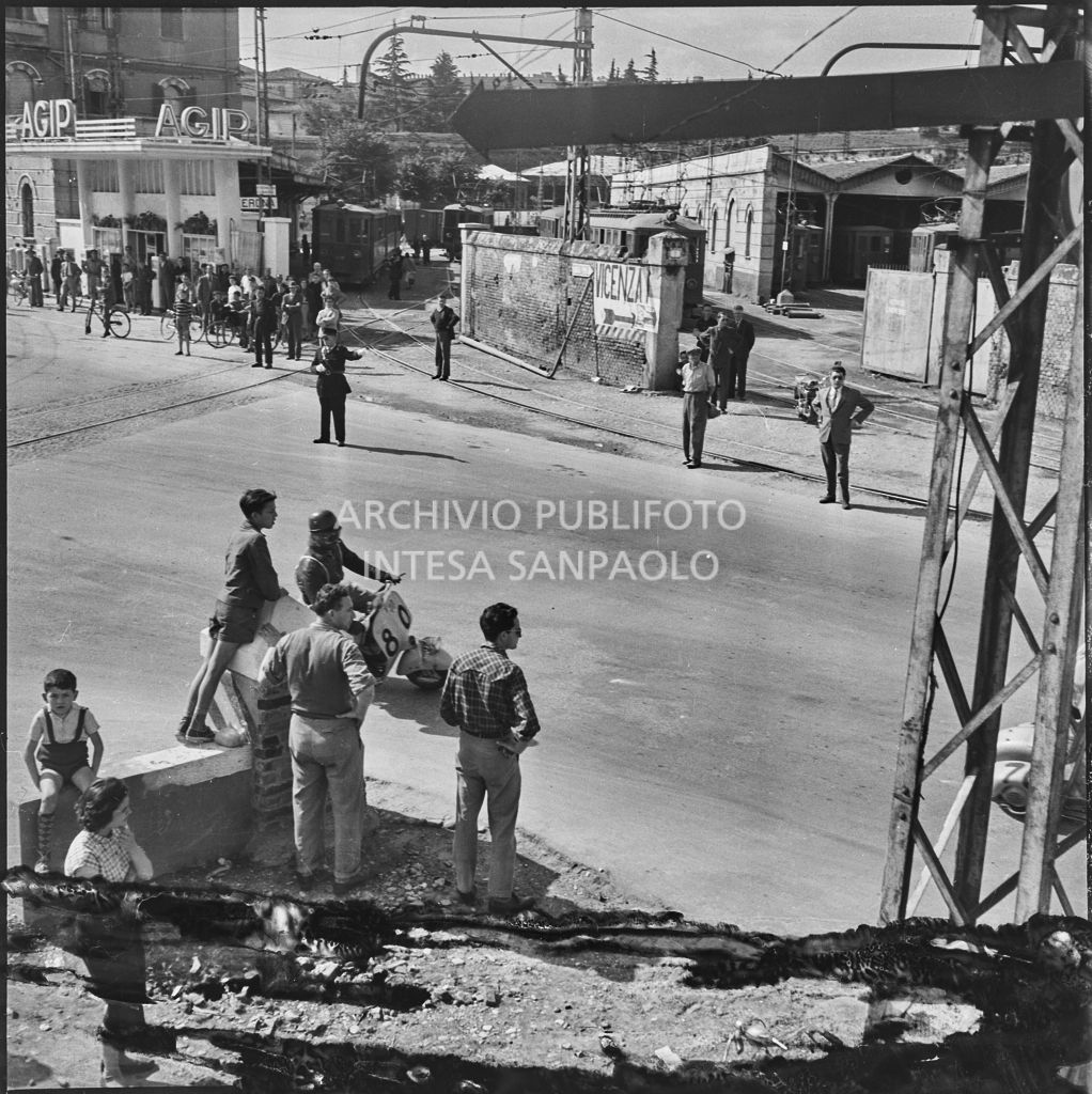 Un concorrente (numero di gara 80) sul piazzale antistante Porta Vescovo a Verona durante la competizione sportiva 1000 Km Vespistica del 1954<br>216619