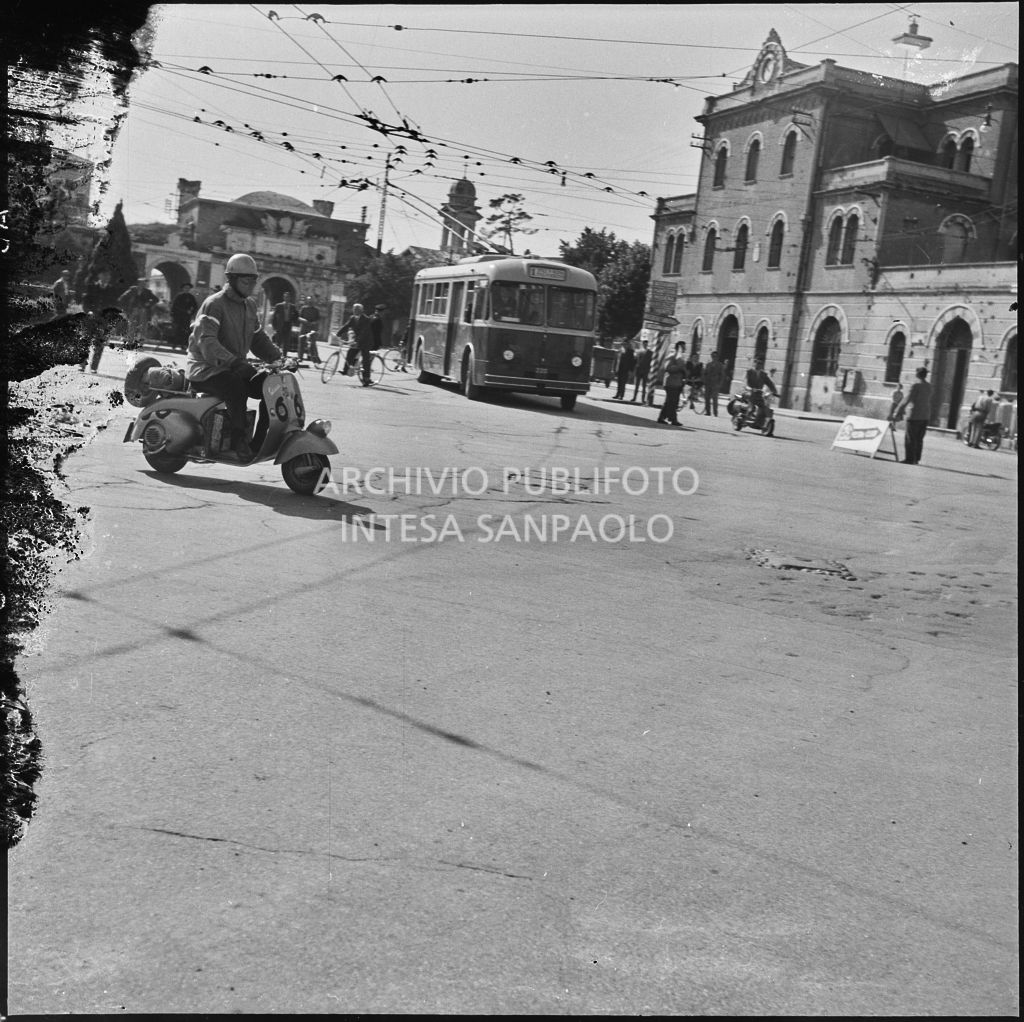 Un concorrente (numero di gara 66) sul piazzale antistante Porta Vescovo a Verona durante la competizione sportiva 1000 Km Vespistica del 1954<br>216637
