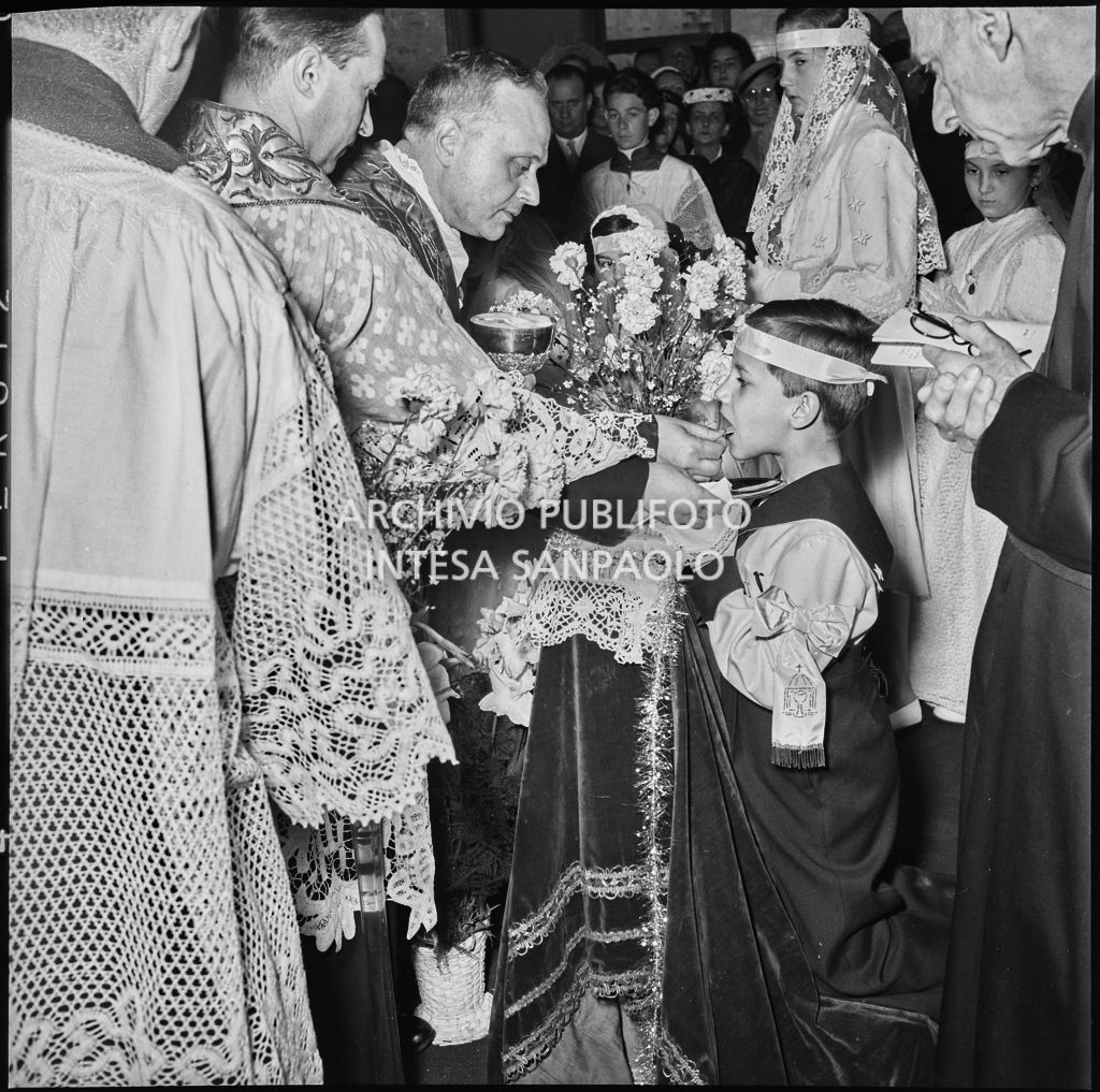 Un bambino dell'Istituto Leone XIII di Milano, in ginocchio davanti all'altare, riceve il sacramento della Comunione<br>216875