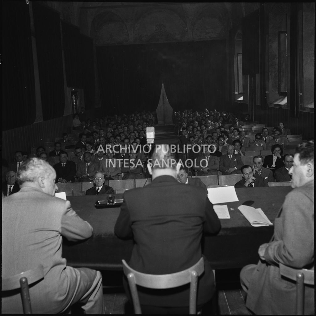 Relatori (di spalle) e pubblico al convegno di studio sulle condizioni del lavoratore nell'impresa industriale organizzata dalla Società Umanitaria nei Chiostri di San Barnaba a Milano. Seduti al tavolo l'onorevole Ezio Vigorelli (primo da sinistra) e il segretario della CGIL Giuseppe Di Vittorio (primo da destra)<br>216964