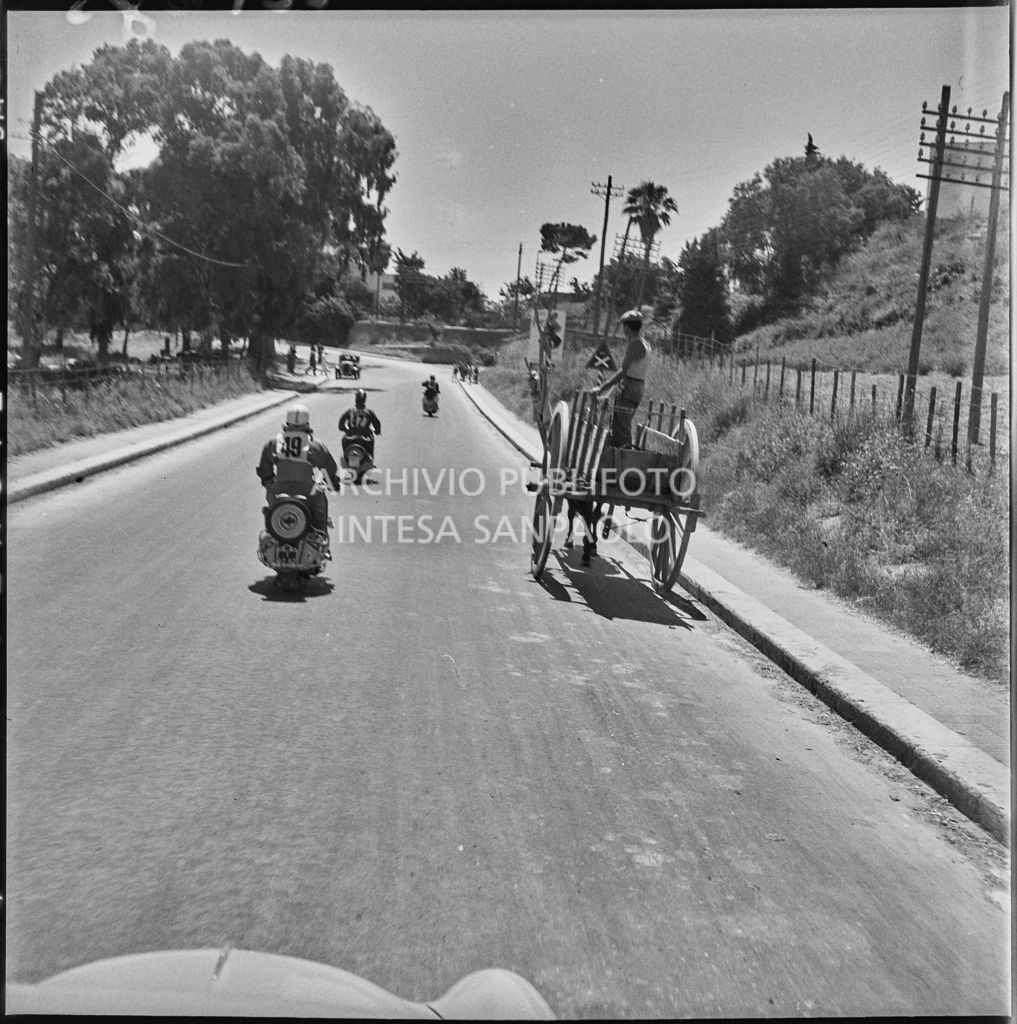 Alcuni concorrenti del 2° Giro Vespistico dei Tre Mari affiancano un carro trainato da un asino durante il percorso<br>221685