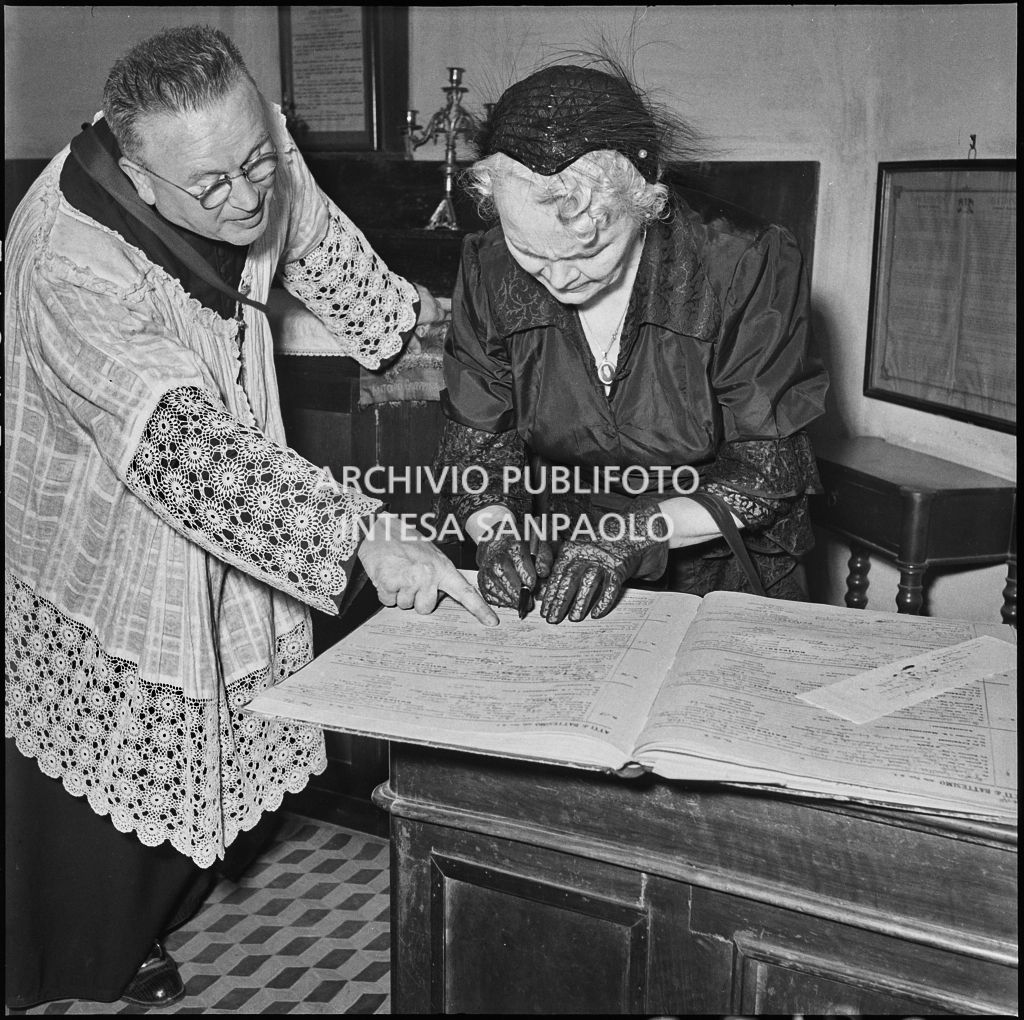 La madrina della figlia del signor Bernardi firma il registro parrocchiale al termine del battesimo<br>221821