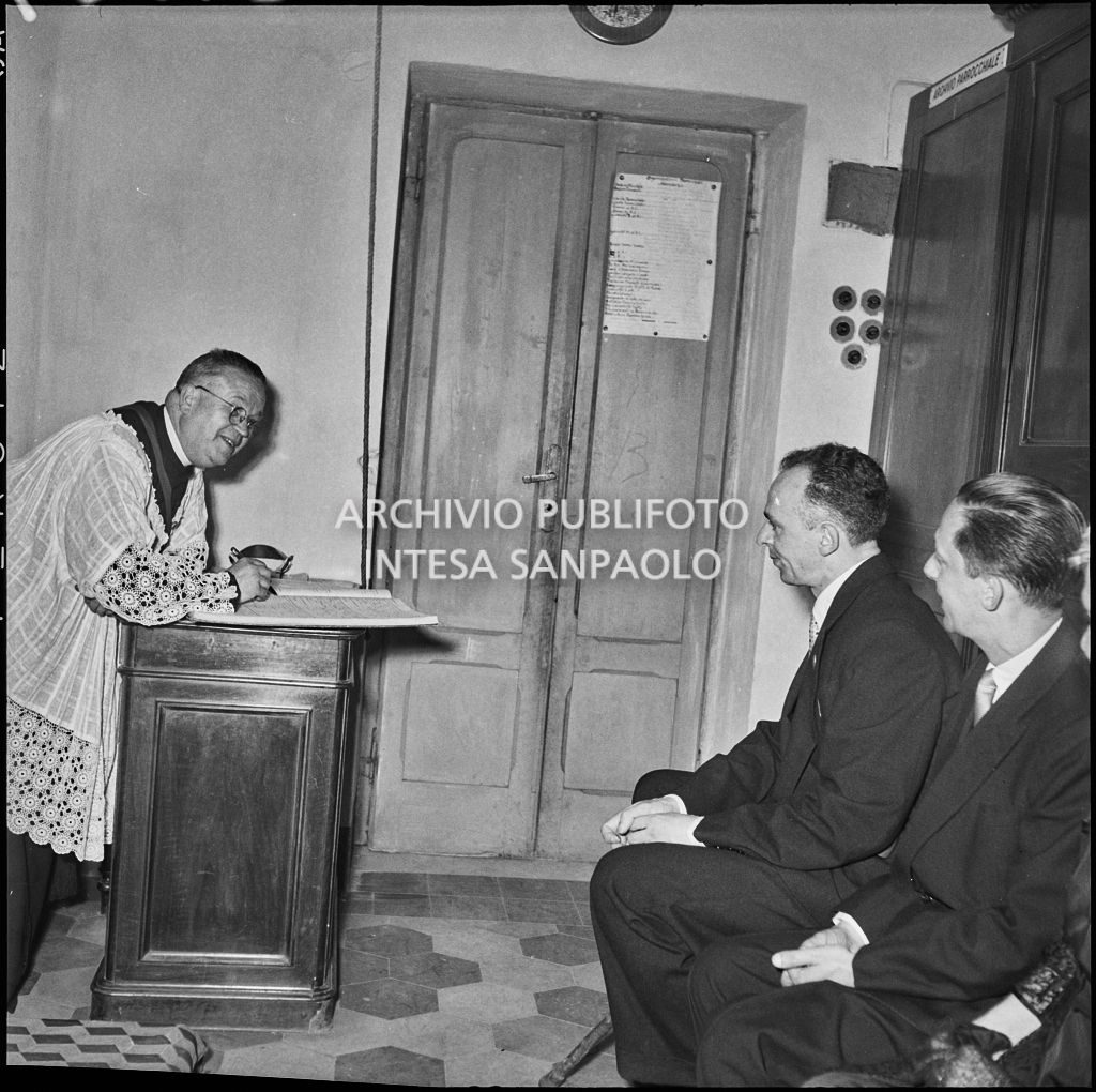 Il sacerdote firma il registro parrocchiale al termine del battesimo della figlia del signor Bernardi<br>221824