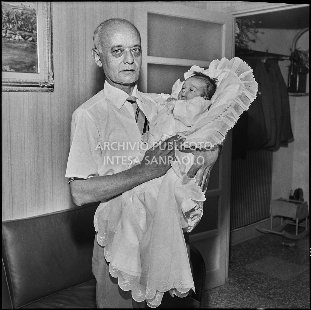 La figlia del signor Bernardi tra le braccia di un uomo nel giorno del suo battesimo<br>221830