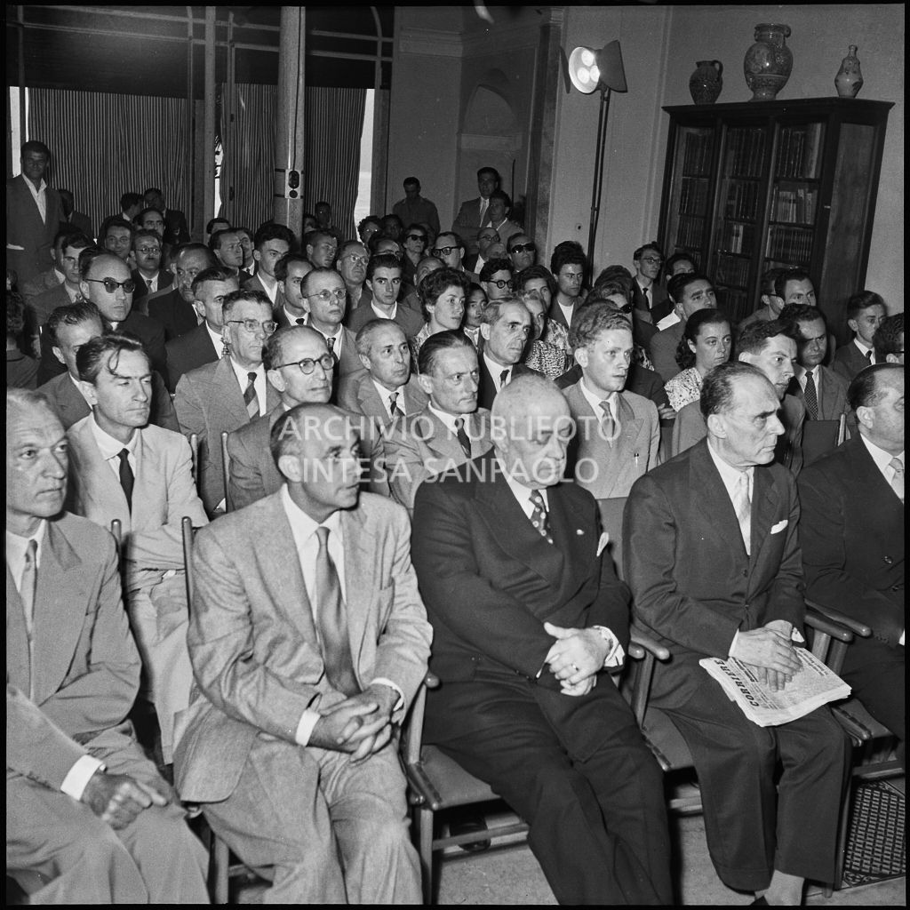 Pubblico all'inaugurazione della seconda edizione del Corso Internazionale di Fisica svoltosi a Villa Monastero a Varenna. Visibili in prima fila il professor Bernardo Rossi (primo da sinistra) e il professor Enrico Fermi (secondo da sinistra) e Eugenio Rossano (terzo da sinistra), in seconda fila il professor Gilberto Bernardini (primo da sinistra)<br>221869