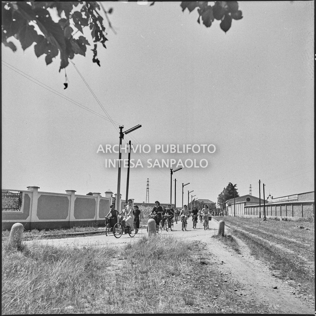 Operaie in bicicletta su una strada accanto alla fabbrica<br>222100