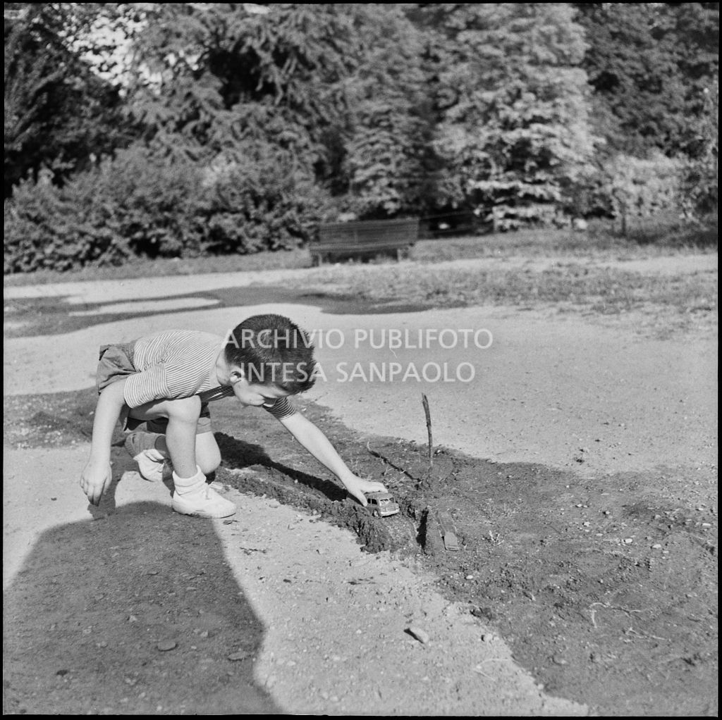 Un bambino gioca con una macchinina in un parco<br>222192