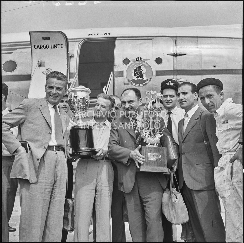 Foto di gruppo sulla piata d'atterraggio dell'aeroporto di Malpensa, davanti all'aereo della KLM Visibile Il pilota José Froilán González (terzo da sinistra) con in mano un trofeo<br>222370
