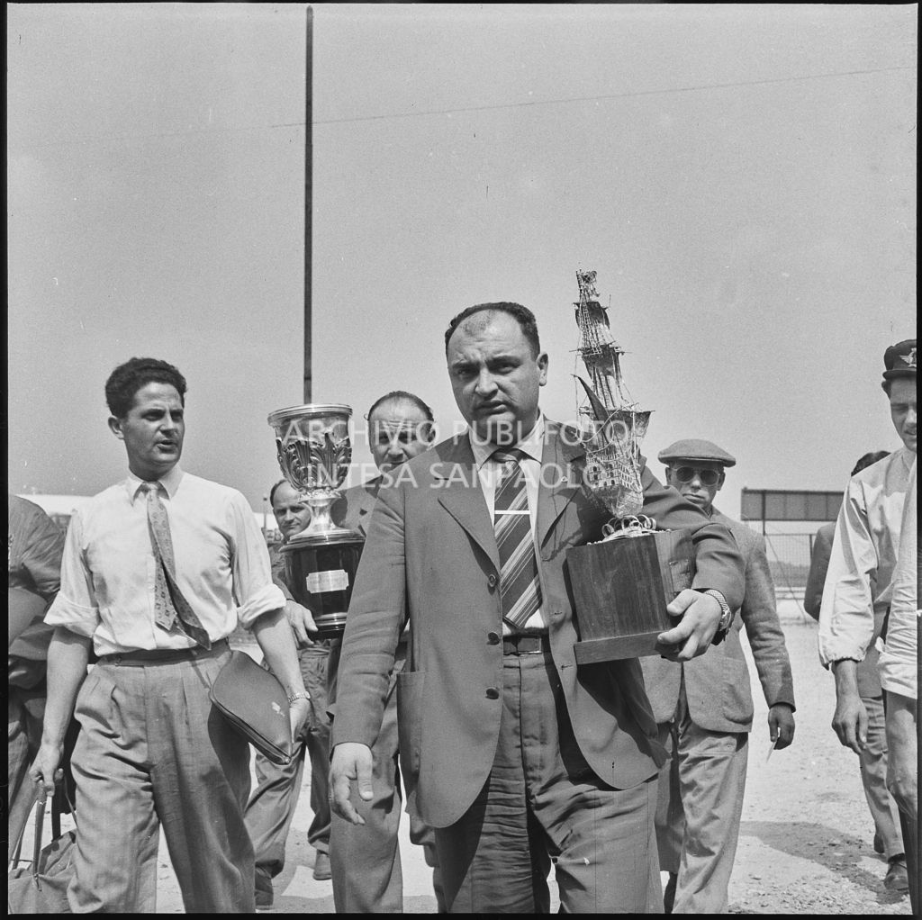 Il pilota José Froilán González sulla piata d'atterraggio dell'aeroporto di Malpensa con in mano un trofeo<br>222371