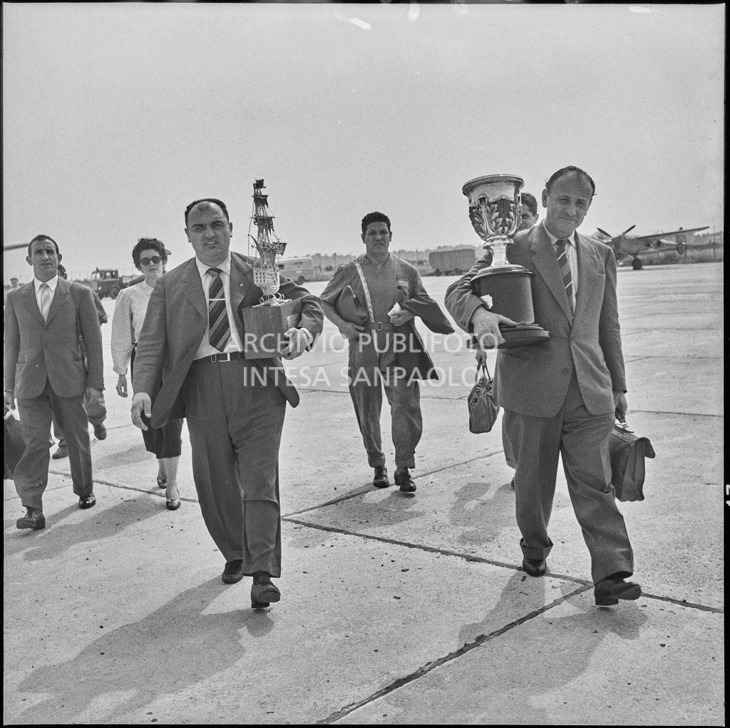 Il pilota José Froilán González (a sinistra) sulla piata d'atterraggio dell'aeroporto di Malpensa con in mano un trofeo<br>222373