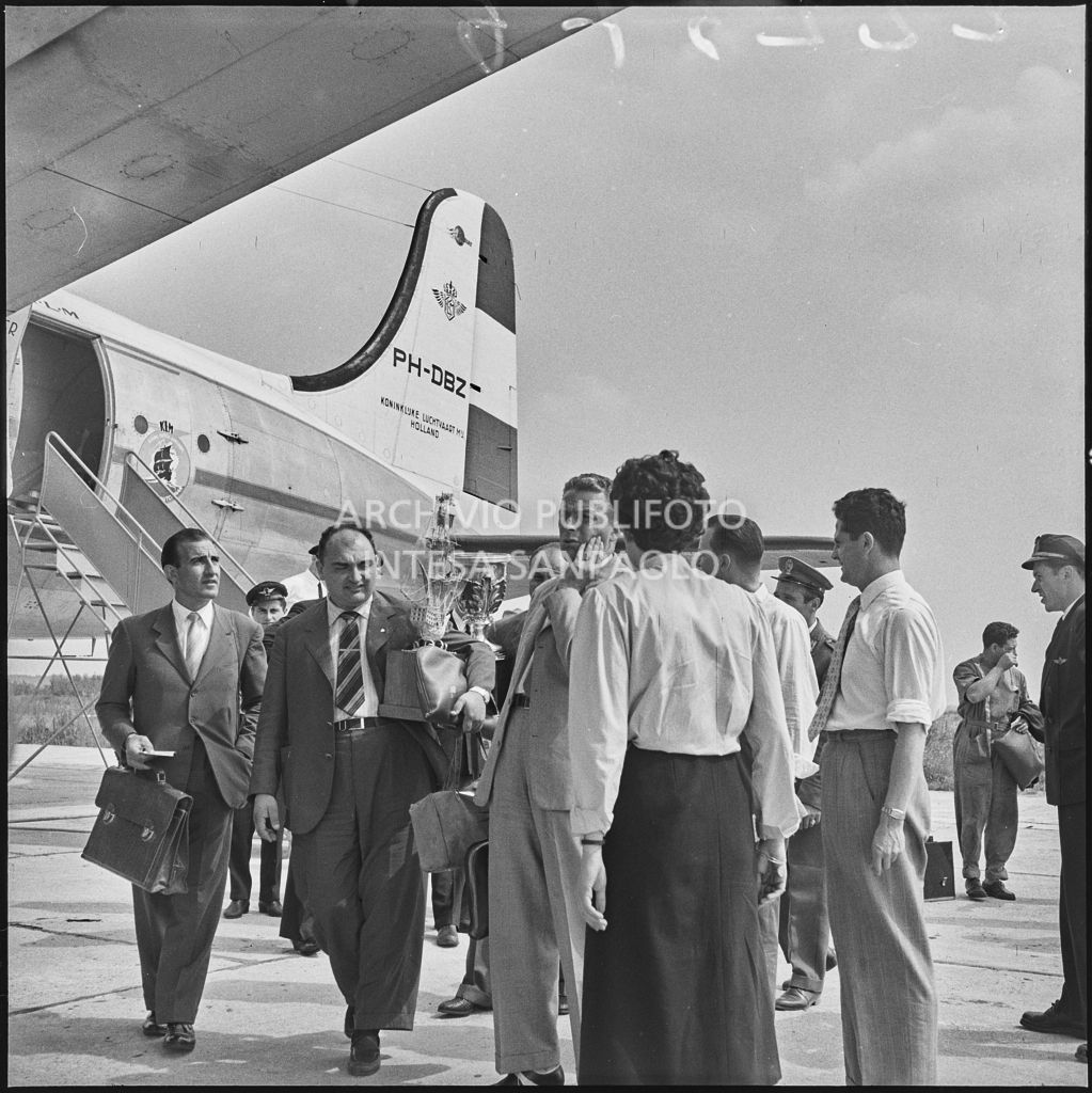 Il pilota José Froilán González (secondo da sinistra) sulla piata d'atterraggio dell'aeroporto di Malpensa con in mano un trofeo<br>222375