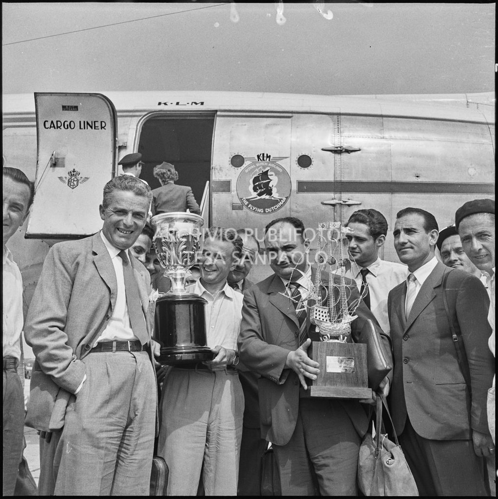 Foto di gruppo sulla piata d'atterraggio dell'aeroporto di Malpensa, davanti all'aereo della KLM Visibile Il pilota José Froilán González (a sinistra) con in mano un trofeo<br>222377