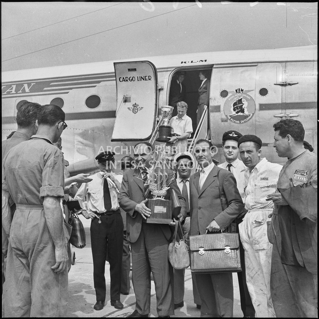 Il pilota José Froilán González, con in mano un trofeo, in posa sulla piata d'atterraggio dell'aeroporto di Malpensa, davanti all'aereo della KLM<br>222378