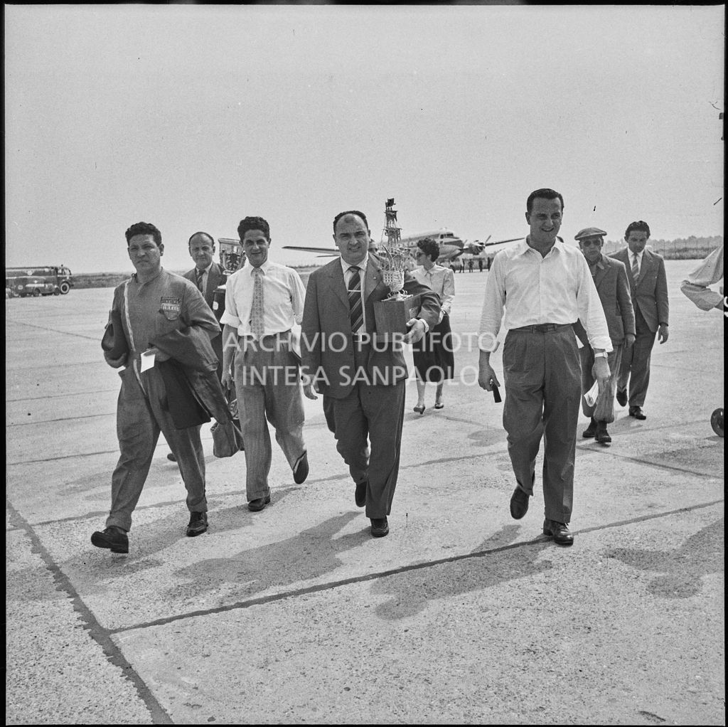 Il pilota José Froilán González sulla piata d'atterraggio dell'aeroporto di Malpensa con in mano un trofeo<br>222380
